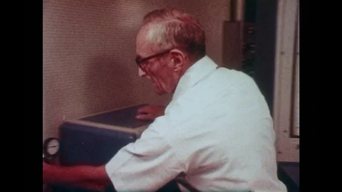 1980s: Man in lab looks through window. High angle shot, men next to engine. Men Stock Footage 83129945