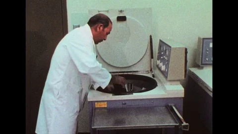 1980s: Man in lab, puts samples in centrifuge / Finger presses button / Close Stock Footage 74783133