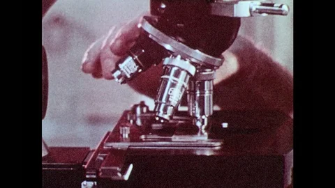 1980s: Man looks through microscope. Animation of nerves and neurotransmitters 库存影片 94465607