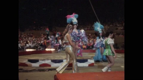 1980s: Pan of circus performers posing in arena. Man talking into microphone. Stock Footage 204885557
