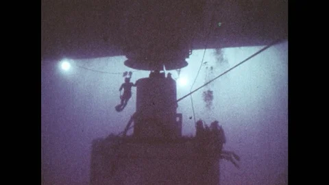 1980s: Scuba divers work to attach an deep-water pipeline to ship. Workers on Stock Footage 86615689