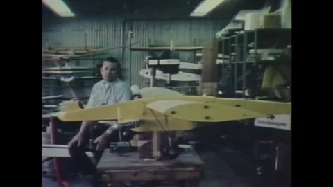 1980s: A sits next to a model of an airplane design in a workshop and talks. Stock Footage 84903990