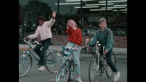 1980s: Three children on bikes, stop in parking lot. Boys compete freestyle on Stock Footage 252860761