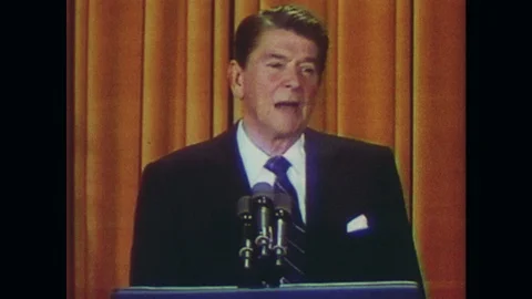 1980s: UNITED STATES: Ronald Reagan speaks into microphone. Orange curtain Stock Footage 104880094