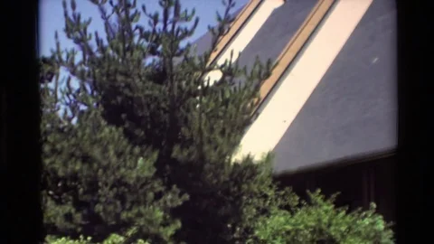 1982: A Large Angular Building with Trees and Parking Area Nearby with People Vídeos de archivo 70212180