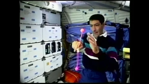 1990s: astronaut in zero gravity spins clacker balls around handle and into one Stock Footage 129277864