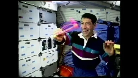 1990s: astronaut in zero gravity spins clacker balls around handle and into one Stock Footage 129277866