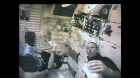 1990s: Astronauts eat in zero gravity. Astronaut knocks floating milk container Stock Footage 128453603
