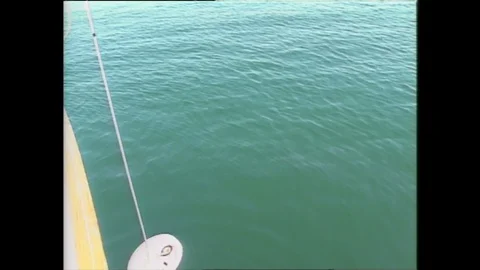 1990s: Boat.  Young man pulls object out of the water.  Girl leans on side of Video stock 128452580