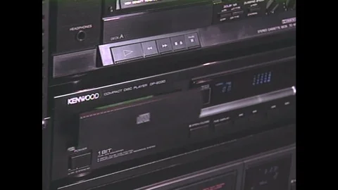 1990s: CD tray of a stereo retracts. White VHS player. Woman turns electric Stock Footage 74735808