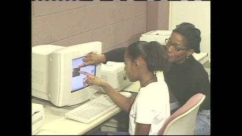 1990s: Classroom, student sits, points at computer monitor, teacher supervises, Video stock 120488670