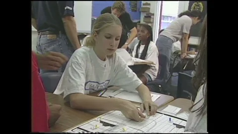 1990s: Classroom.  Students talk and play game.  Rulers on grid.  Person fills Stock Footage