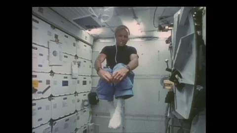 1990s: Floating astronaut struggles and waves arms and legs. Astronaut paddles Stock Footage 128453614