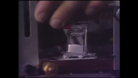 1990s: Hand moves machine elements.  Text reads "Dendrites Grown in Stock Footage 128006049