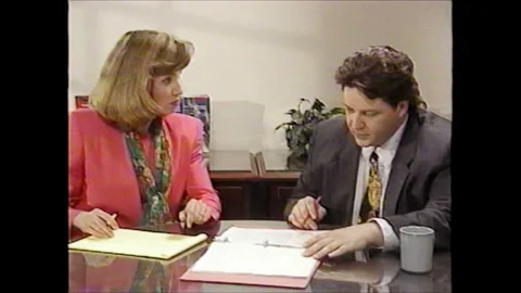 1990s: man and woman at office table talk with notepads and pens, woman talks, Stock Footage
