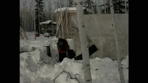 1990s: Man digs hole in ice. Man pulls beaver out of hole in ice. Fish hanging Stock Footage 162326883