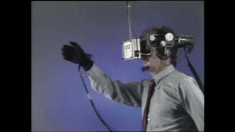 1990s: man with head-mounted virtual reality visor reaches out with data-gloved Vidéo 128453291