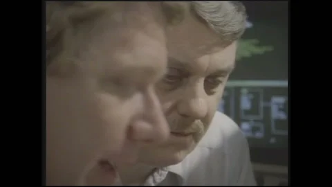 1990s: Man points at computer screen while talking to man. Men look at info on Stock Footage 146555224