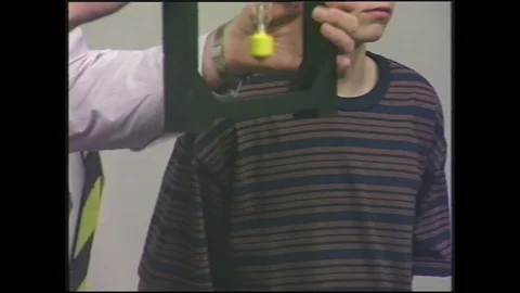 1990s: Man stands talking, holding rectangle frame next to boy, dangling object Stock Footage 128213030