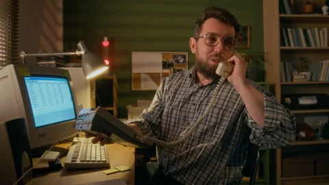 1990s Man Working on Retro Computer at Home and Talking on Landline Telephone Stock Footage 327235011
