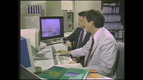 1990s:  Men work on computer and point to screen. Man operates robotic camera Stock Footage 144702418