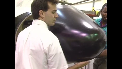 1990s: Two men dethatch the nose from an aircraft.  A simple computerized Video stock 74735391