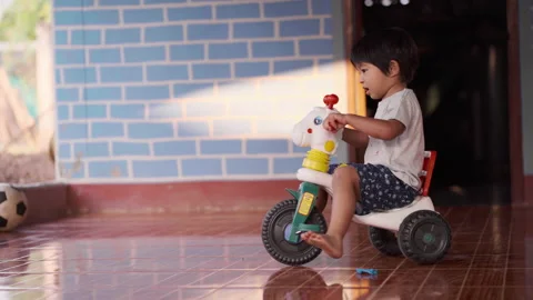 2-3 year boy playing 3 tire bike toy in house Stock Footage 149917071