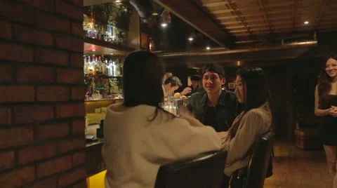 2 angles - bartender mixes a drink to attractive Taiwan group at trendy bar Stock Footage 46705834