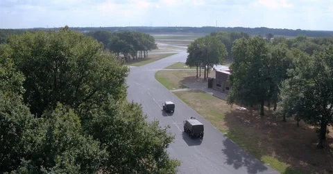2 army trucks driving along a road on a military airfield Stock Footage 70260004
