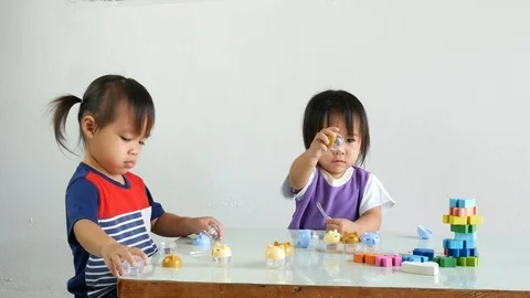 2 Asian child playing open, shut a screw cap of round jar on table at  room. Stock Footage 104642029