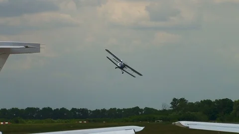 An-2 biplane performs combat turn and flies over runway, waving its wings. Stock Footage 106491801