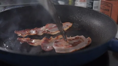 2 bits of bacon cooking in frying pan, slider shot. Close up Stock Footage 96202279