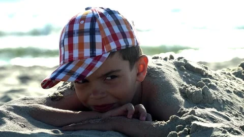 2 a boy in a cap lies in the sand, a girl buries a boy in the sand, summer, Stock Footage 264291948