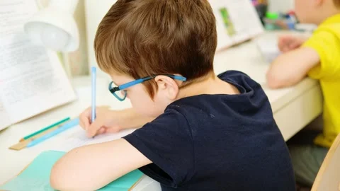 2 boys sit and write in notebooks at the table, at home. Stock Footage 243445393