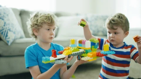 2 boys work together to build a spaceship out of building blocks in slow motion Stock Footage 127549537