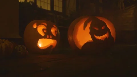 2 carved lit pumpkin outside the front of a house halloween with smoke Stock Footage 137329795