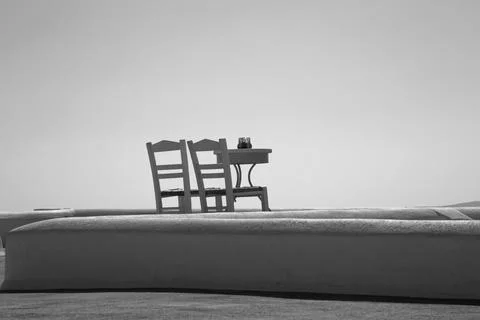 2 chairs and a table by themselves on a roof in Santorini Stock Photos