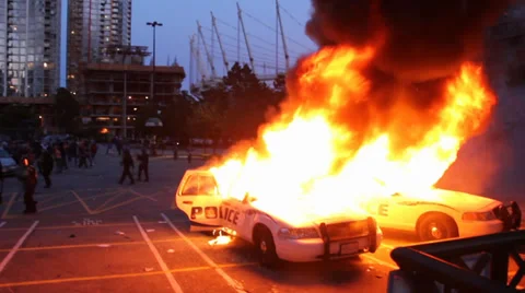 2 cop cars burn while riot officers throw tear gas Stock Footage