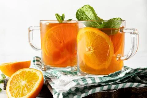 2 cups of tea with orange, mint on a towel on a white background Stock Photos