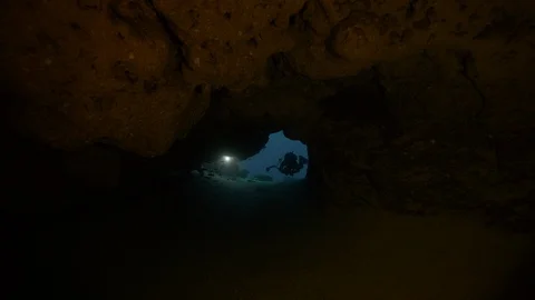 2 diver with torches enter in a cave with a sandy bottom, Red Sea, Egypt Stock Footage 105544543