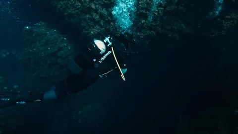 2 divers with bubbles fall among the rocks, Ustica, Sicily, Mediterranean sea Stock Footage 125149089