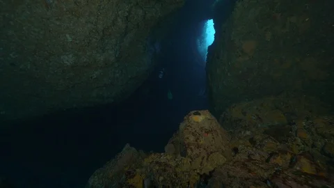 2 divers come out from a crack between rocks to the open sea, Ustica, Med sea Stock Footage 125252377