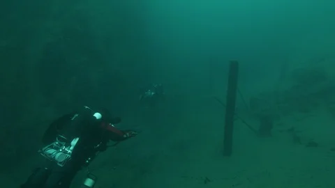 2 divers swim on the remains for the dam construction, San Domenico lake, Italy Stock Footage 108690050