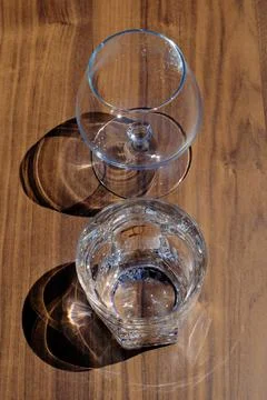 2 empty glasses and their shadows on a wooden table Stock-Fotos