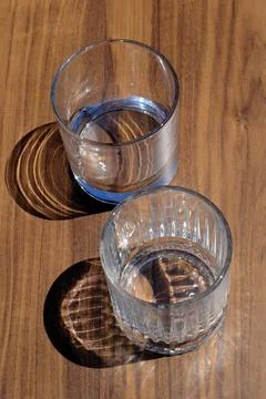 2 empty glasses and their shadows on a wooden table Foto stock