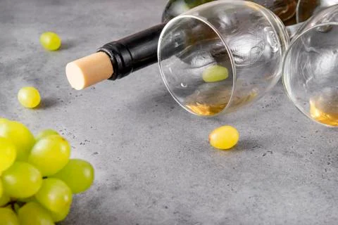 2 empty glasses, a bottle, a bunch of green grapes on a gray background close Stock Photos