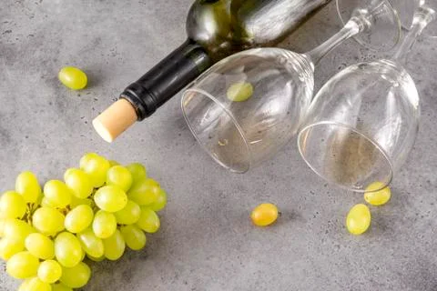 2 empty glasses, a bottle, a bunch of green grapes on a gray background Stock Photos