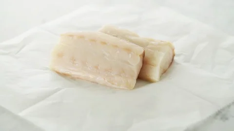 2 fresh Cod fillets on grease-proof paper on marbl Stock Footage 92145557