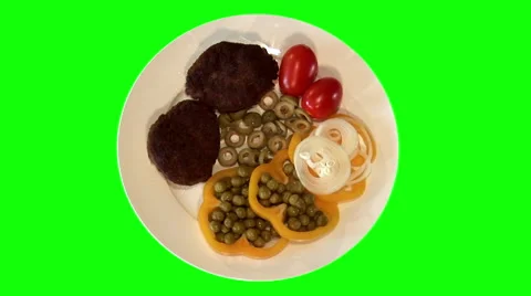 2 fried beef chops with raw vegetables on plate, top shot Stock Footage 47546785