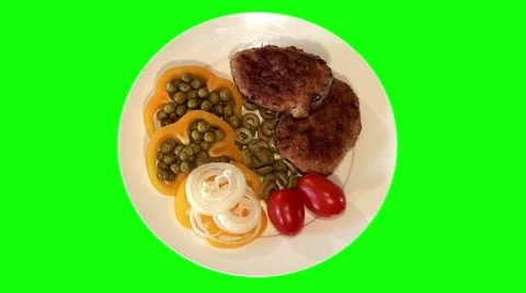 2 fried pork chops with raw vegetables on plate, top shot Stock Footage 47546474